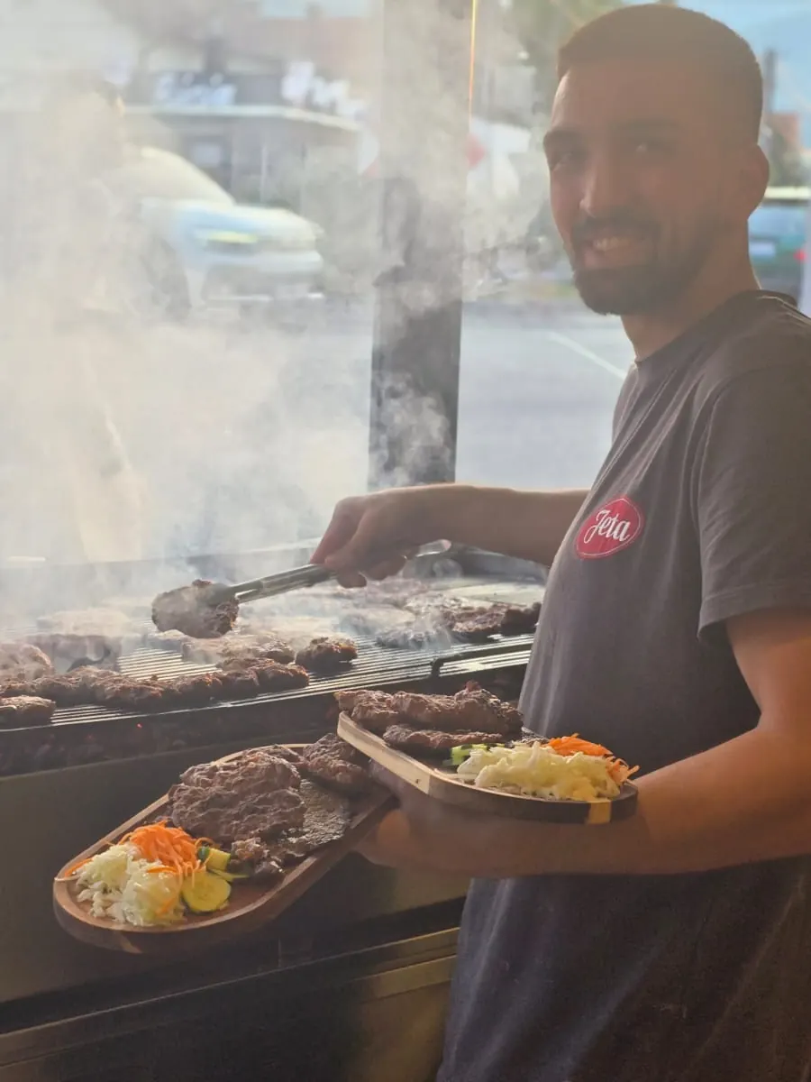 Kuzhinieri i Jeta 2000 duke servirur pjata zgare me sallatë pranë zgarës